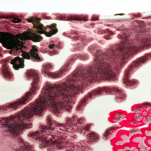 Nahaufnahme lila Samtkissen mit paspelierten Kanten mit floralem Blumenmuster.