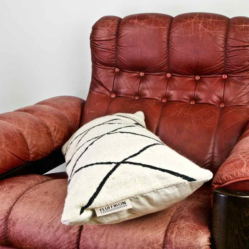 Black and white Fluffikon Kilim pillow on a vintage red leather chair.