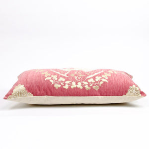 Rosa Dekokissen mit floralem Muster in gold auf dem Boden liegend.