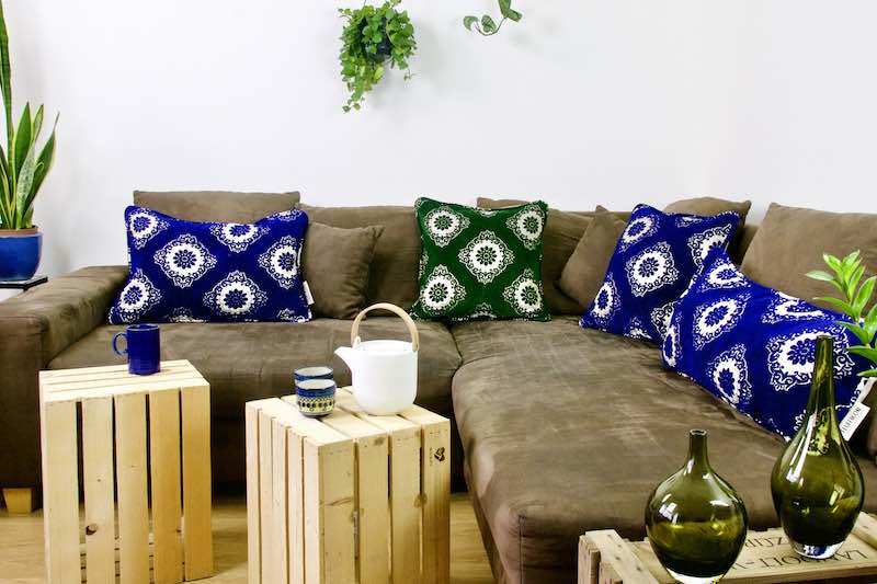 Three blue and green Fluffikon velvet pilloes on a living room couch.