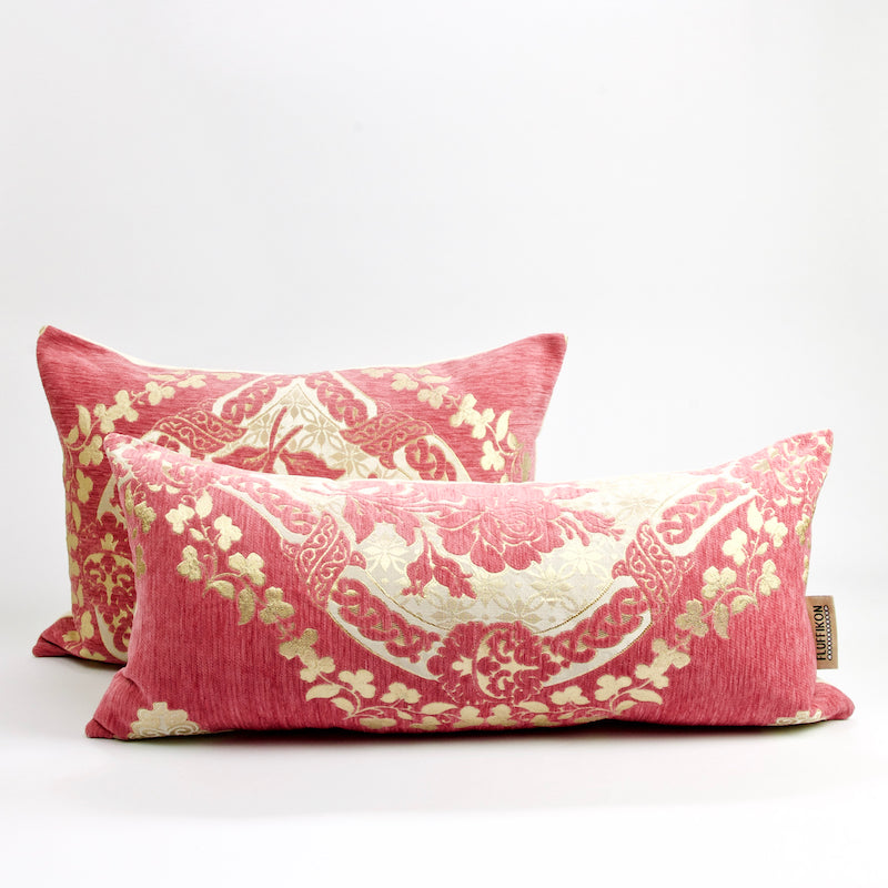 Two blush pink Fluffikon lumbar pillows with golden flower motif. The lumbar pillows have a traditional Moroccan design.