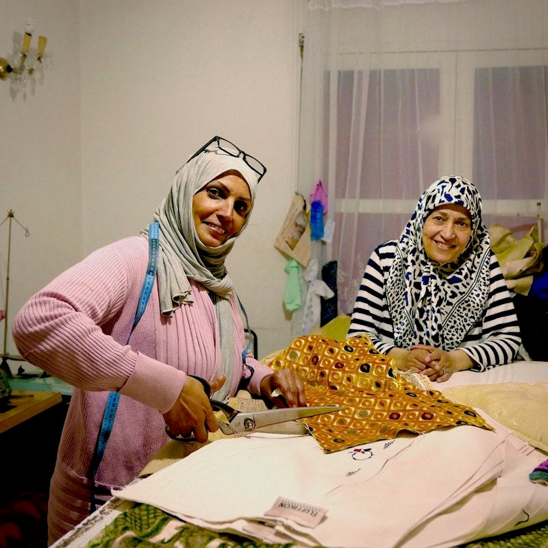 Two women holding fabric for decorative pillows.