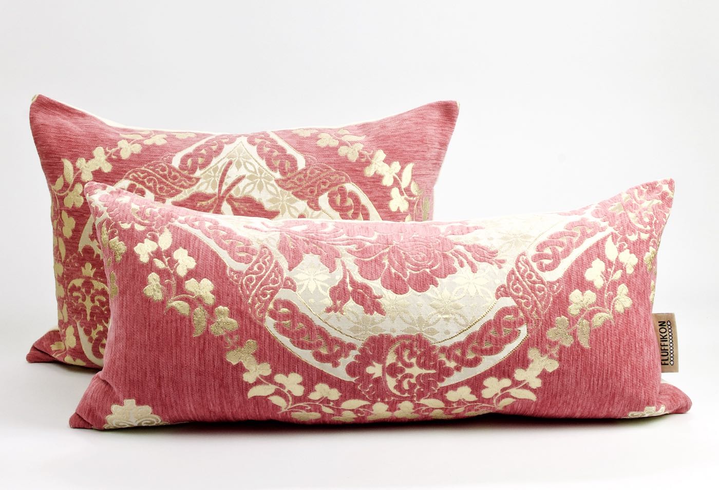 Zwei rosa Fluffikon Dekokissen mit goldenen Blumen Muster. Beide Kissen stehen voreinander.