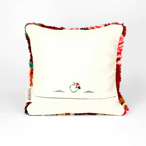 The back of a standing red Berber pillow made from a vintage wool rug.