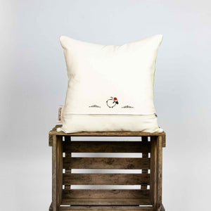 Fluffikon silk square pillow made from green moroccan fabric. The pillow is shown from the back on a wooden box. Size 45x45 cm.