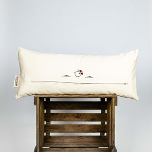 Fluffikon silk lumbar pillow made from golden moroccan fabric. The pillow is on a wooden box shown from the back.