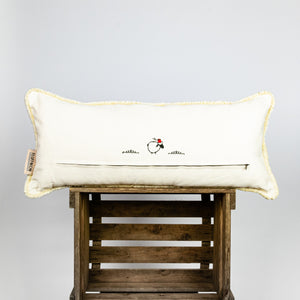 Fluffikon velvet lumbar pillow made from beige moroccan fabric. The pillow is on a wooden box. The pillow back is shown.