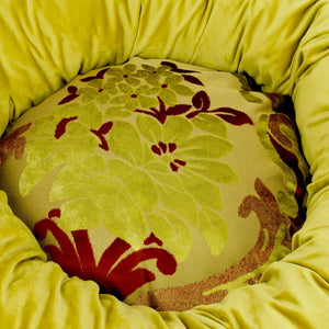 Rundes Donut Hundebett aus gelb rotem Samtstoff.