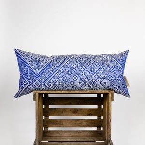 Blue-white decorative lumbar pillow made from silk with moroccan pattern. Pillow on a wooden box.