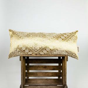 Sofakissen Gold aus Seide. Das goldene Fluffikon Kissen hat typische marokkanische Muster. Es steht auf einer Holzbox.