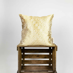 Zierkissen Gold auf einer Holzbox. Das goldene Kissen hat typische marokkanische Muster.