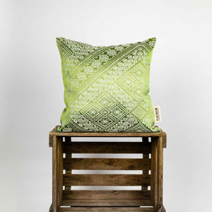 Fluffikon silk square pillow made from green moroccan fabric. The pillow is on a wooden box. Size 45x45 cm.