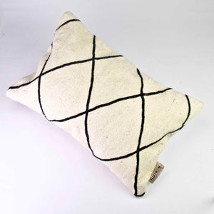 Black and white Fluffikon Kilim throw pillow on a white floor.