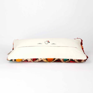 Vintage Berber pillow in red. The cushion is laying on a white ground.