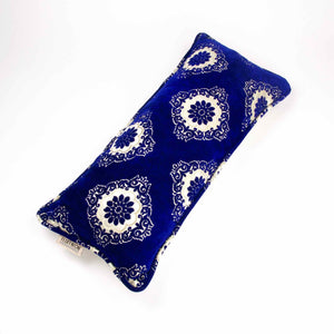 Großes blaues Samt Sofakissen vor weissem Hintergrund.