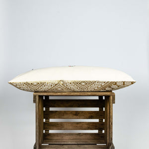 Fluffikon silk lumbar pillow made from golden moroccan fabric. The pillow is on a wooden box shown from the side.