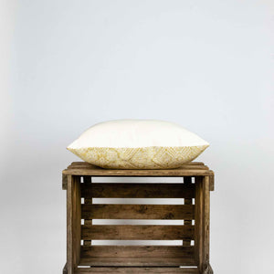 Fluffikon silk square pillow made from golden moroccan fabric. The pillow is on a wooden box shown from the side.