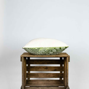 Fluffikon silk square pillow made from green moroccan fabric. The pillow is shown from the side on a wooden box. Size 45x45 cm.