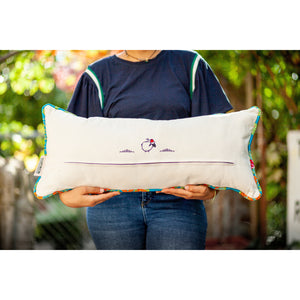 Woman holding a blue decorative lumbar pillow made from shiny brocade with colourful flowers embroidery. Back of the pillow made from white cotton.
