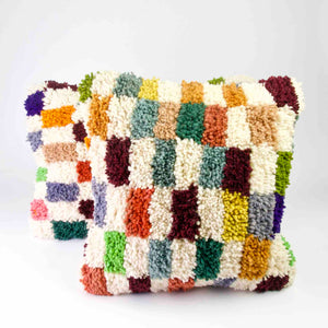 Zwei Fluffikon Kinderzimmer Kissen vor weissem Hintergrund. Die Kissen sind bunt kariert.