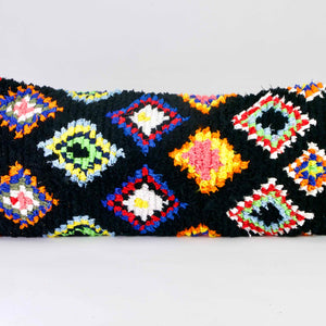 Black Fluffikon Boucherouite lumbar pillow. The Moroccan pillow is made from upcycled clothes. It has colorful patterns in yellow, red, blue and green.
