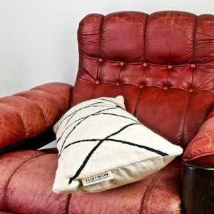 Black and white Fluffikon Kilim pillow on a red leather chair.
