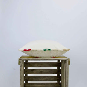 Side view of a velvet square pillow. The pillows is placed on a wooden box.