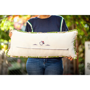 Fluffikon velvet lumbar pillow. Grey and green colours with flowers on it. Pillow shown from the back held by a woman. Size 35x70 cm.