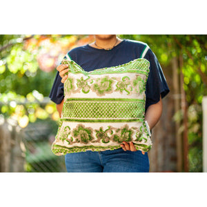 Fluffikon grey green decorative pillow with flowers made from moroccan velvet fabric. The throw pillow is shown from the front held by a woman.