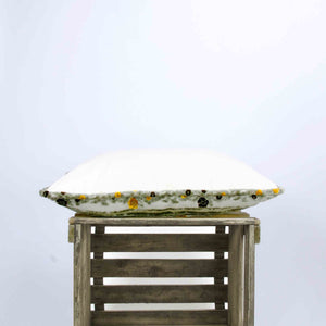 Side view of a big velvet decorative pillow with brown and yellow flowers.