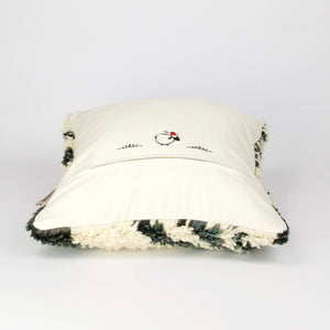 Vintage rug pillow made from a Moroccan carpet lying on the ground.