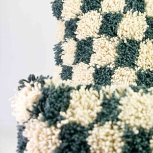 Two checkered Moroccan pillows standing in front of each other. Focal point is on the pillow in the back.