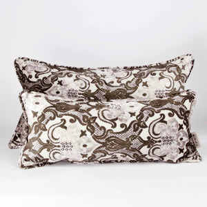 Two large couch pillows made from brown beige velvet fabric. The pillows are standing in front of each other.