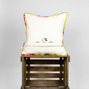 Back of yellow square Brocade pillow on wooden box.