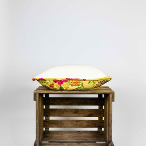 Side of yellow square Brocade pillow on wooden box.