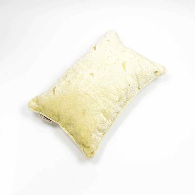 Beige velvet cushion in front of white background.