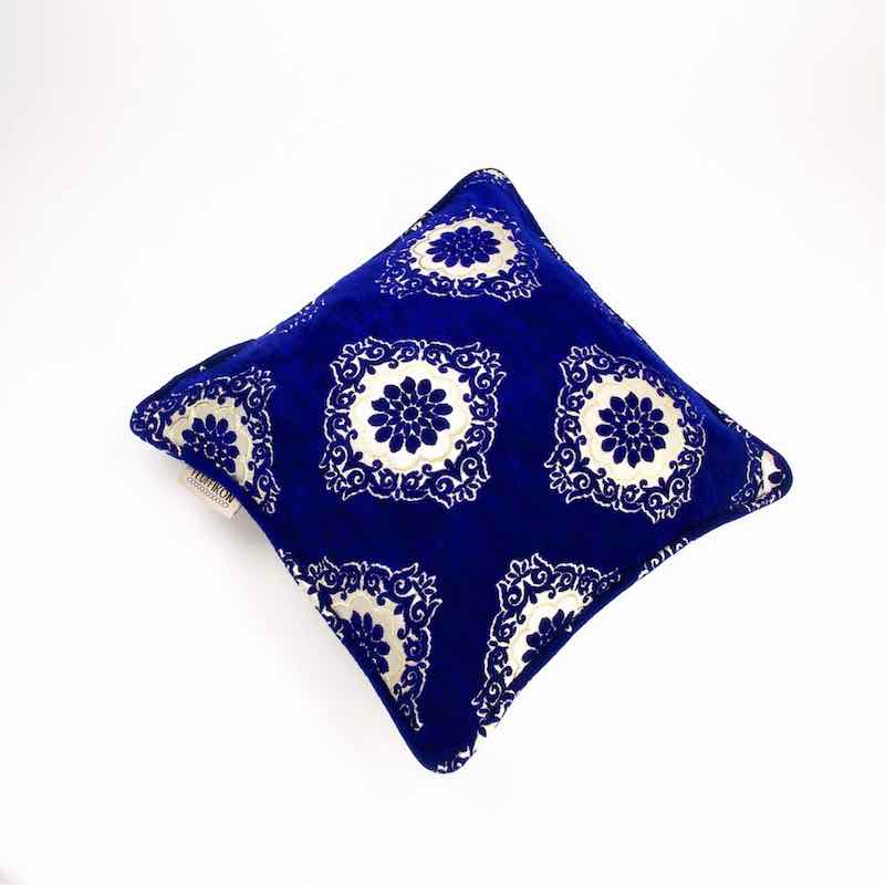 Marokkanisches blaues Sofakissen aus Samt vor weissem Hintergrund. 