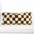 Earthly brown white checkered Fluffikon Berber lumbar pillow in front of white background.