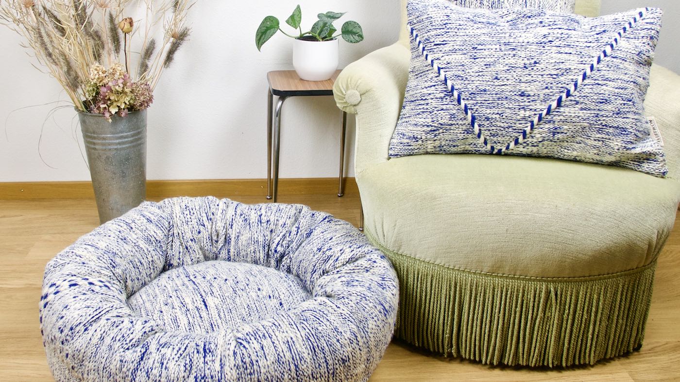 Blue and white Fluffikon Kilim cat bed that is made from a Moroccan rug. A Kilim throw pillow is shown in the back.