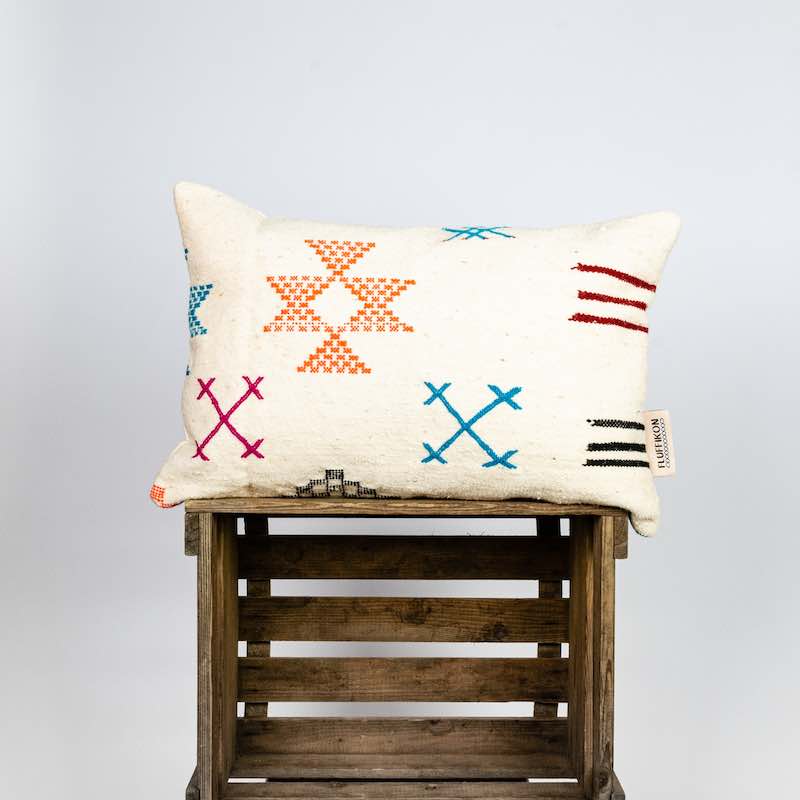 Fluffikon Kilim pillows standing on a wooden box.