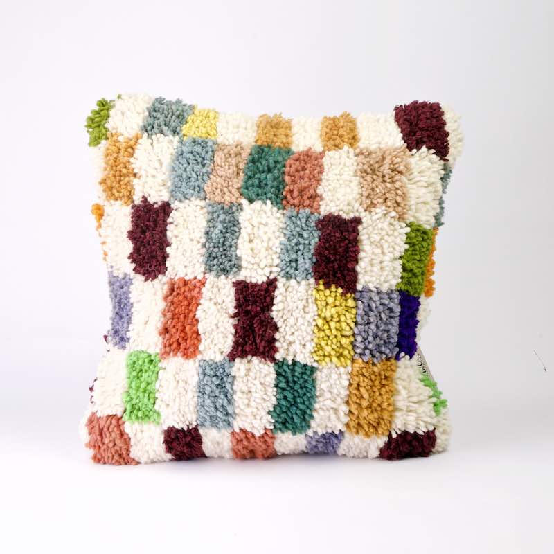 Quadratisches Fluffikon Kinderzimmer Kissen. Das Kissen ist bunt kariert.