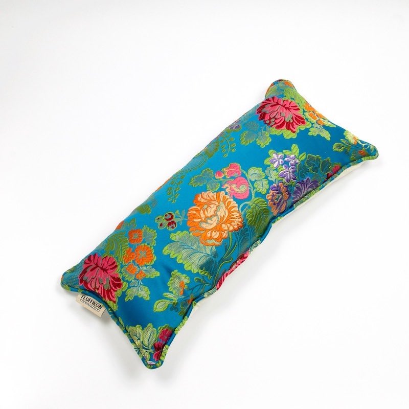 Blue brocade cushion in front of white background.