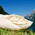 The inner wool filling of a Fluffikon pillow is shown. The pillows is lying on gras in Swiss mountains.