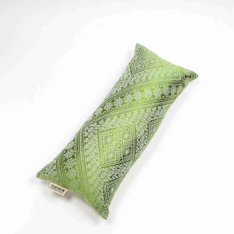 Green silk cushion in front of white background.