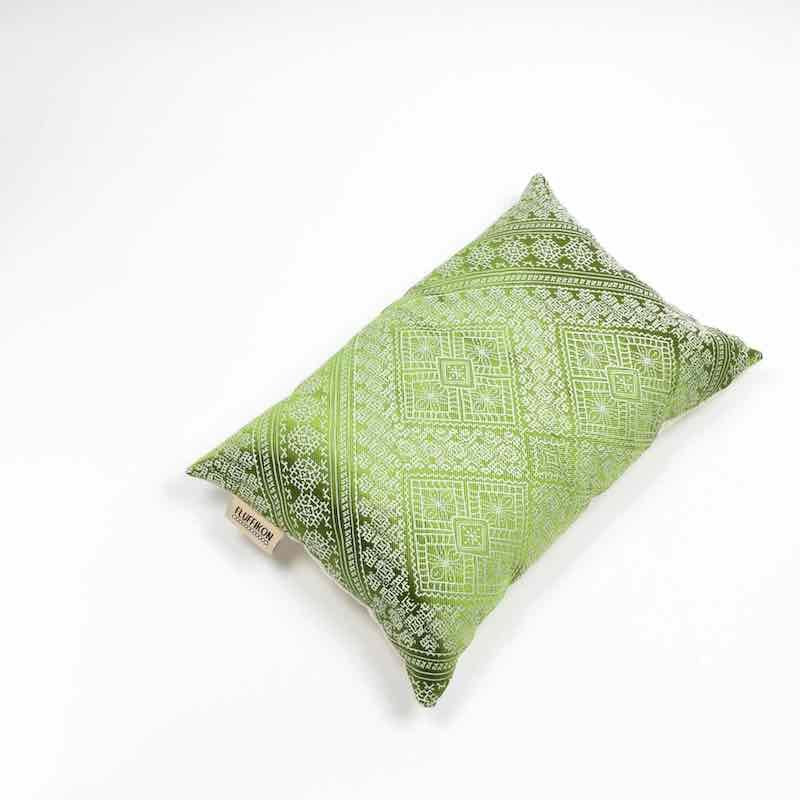 Green silk cushion in front of white background.