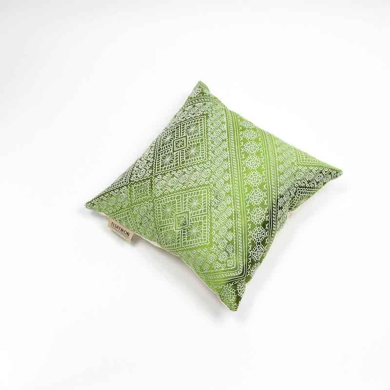 Green silk cushion in front of white background.