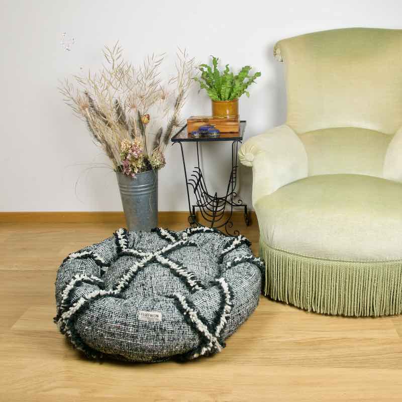 Kilim dog bed in front of a green velvet chair. The customized dog bed is made from a Moroccan Kilim wool rug.