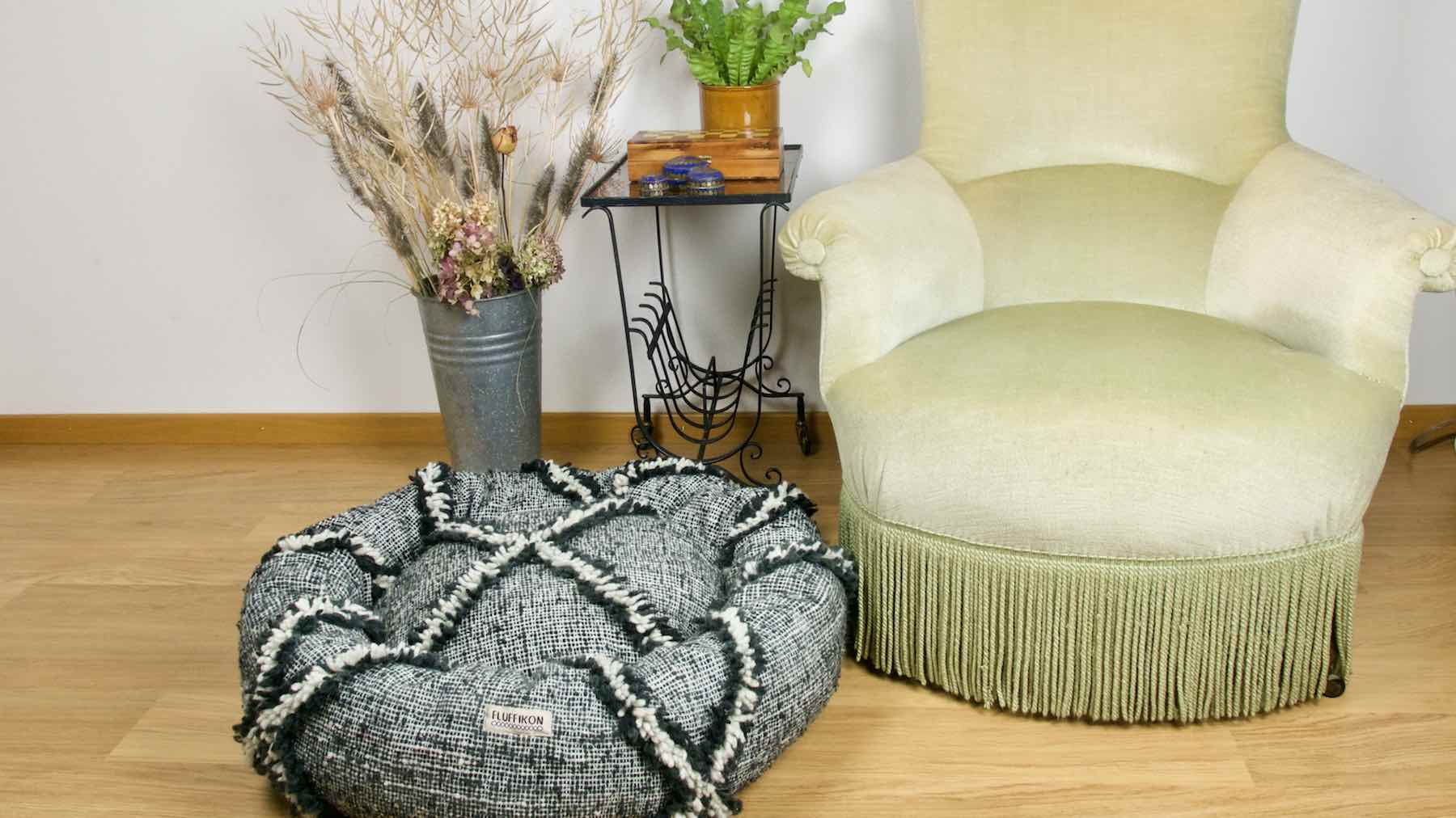 Kilim dog bed in front of a green velvet chair. The customized dog bed is made from a Moroccan Kilim wool rug.