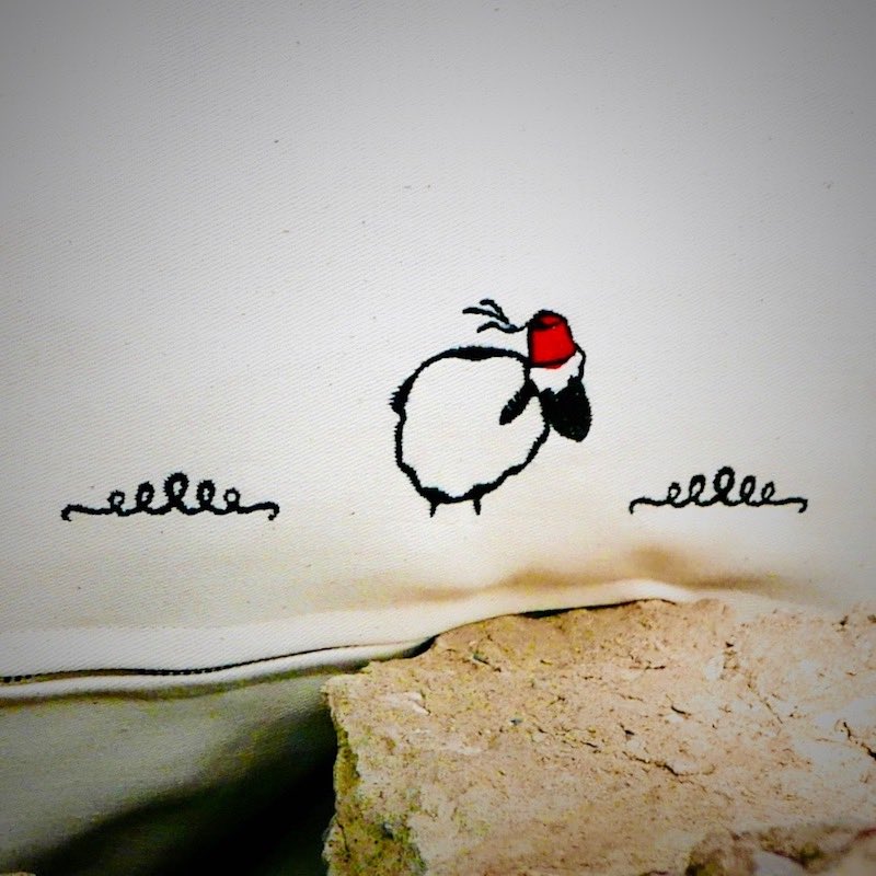 Sheep with a moroccan hat stitched on a decorative pillow.