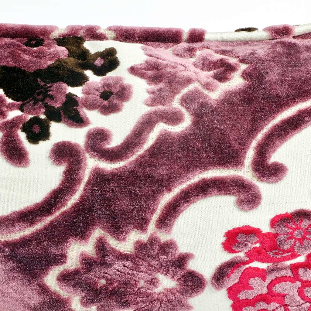 Nahaufnahme lila Samtkissen mit paspelierten Kanten mit floralem Blumenmuster.